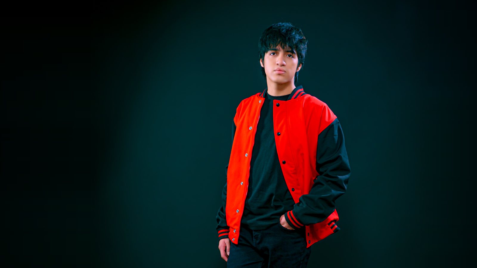  de pie, con su chaqueta varsity roja y negra